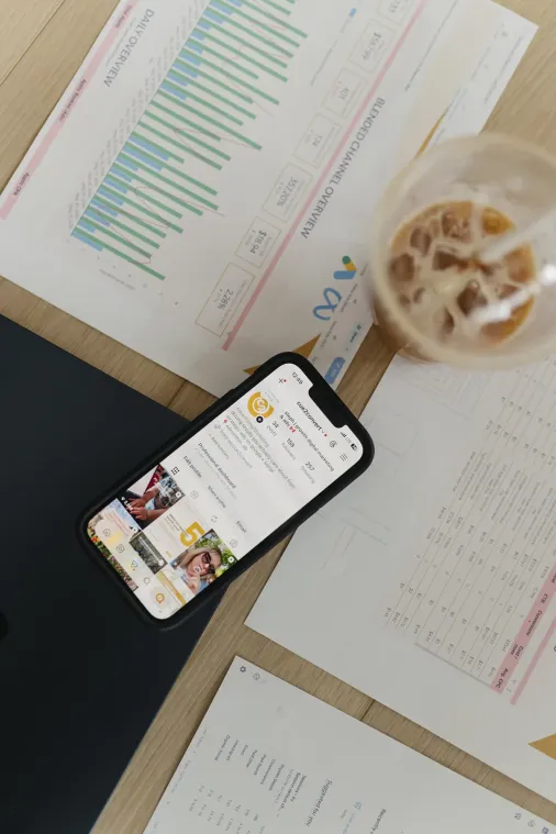 Overview shot of a phone highlighting Cue2Convert's Instagram page that's sitting on top of a graph showcasing the results of a client's paid advertising in Edmonton.