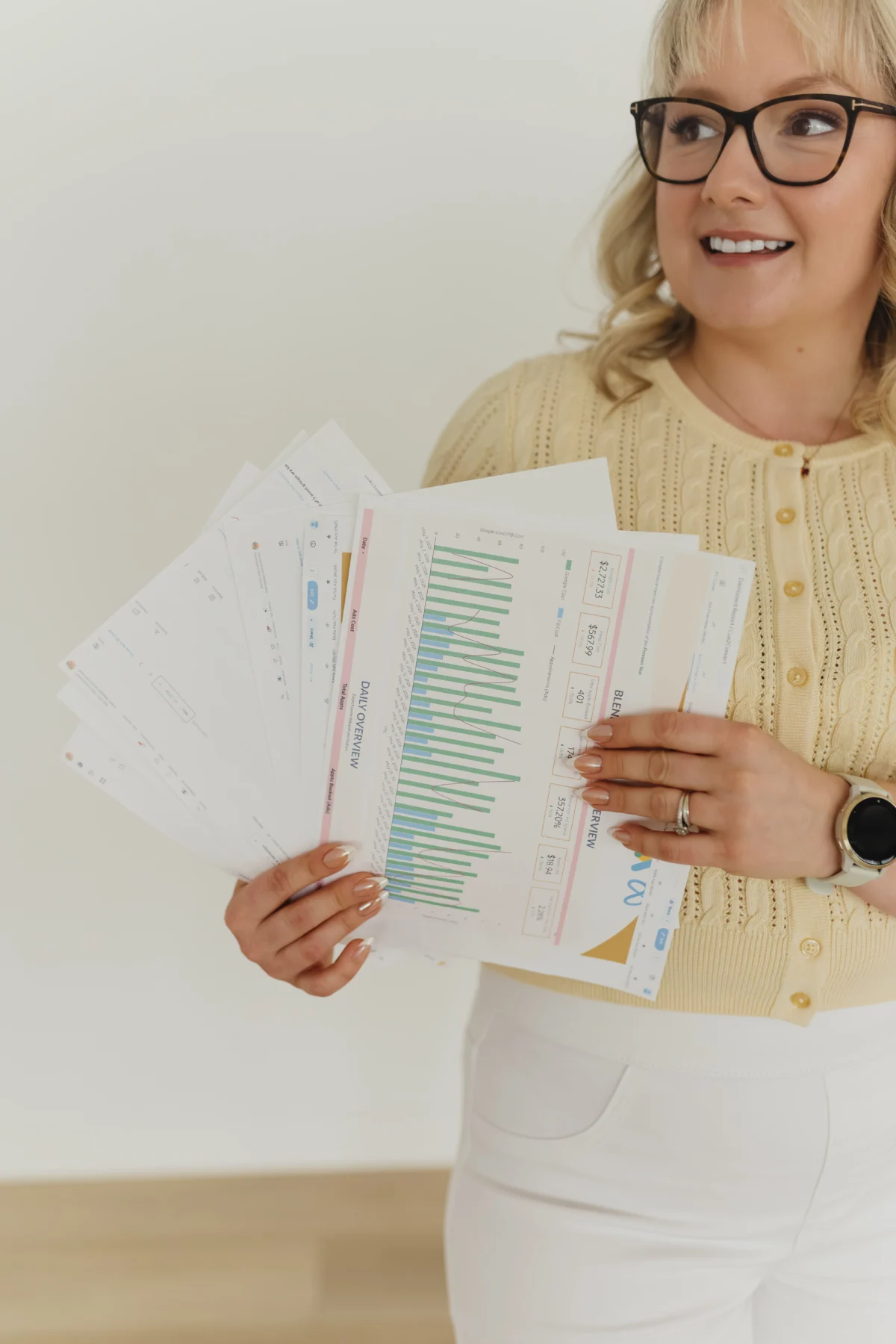 Stephanie, owner of Cue2Convert, holding printed out screenshots of paid advertising Edmonton results.